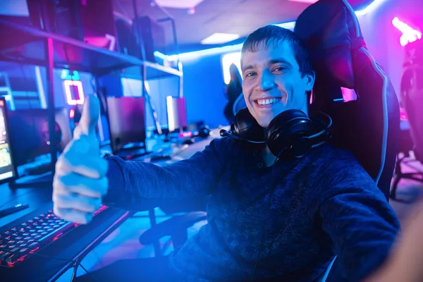 Profesional gamer hombre sonrisa haciendo foto selfie y jugando torneos en línea videojuegos ordenador con auriculares — Foto de Stock