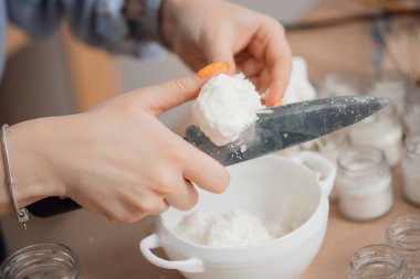 Önlüklü genç zanaatkar, sanat stüdyosunda el yapımı mum üretimi için parafin cilası kesiyor. Küçük işletme sahiplerini kavra