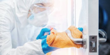 Tıbbi personel kapı kollarını dezenfekte etti. Virüs ve mikroplar biyokimyasal giysi ve pankarttaydı.