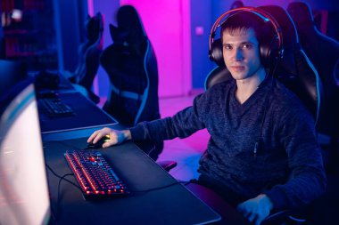 Portre genç adam profesyonel oyuncu çevrimiçi oyunlar oynuyor kulaklıkla bilgisayar, neon renk