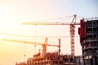 Beton dökmek için vinçleri ve demir takviyesi olan günbatımı siluet inşaat sahası. Konut stokunu artırma kavramı