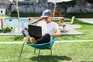 Latin Adam güzel bir terasta dizüstü bilgisayarla çalışıyor. Akıllı telefon ve bilgisayar kullanıyor. Mexico City 'de ev işlerinde yan yana oturuyor.