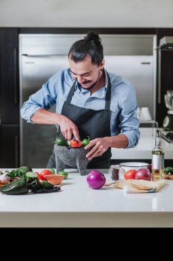 Latin adam evde yemek pişiriyor. Salata veya Meksika sosu hazırlıyor. Meksiko 'daki evde.