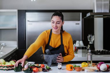 Latin kadın Meksika sosu pişiriyor. Meksiko 'daki evde mutfakta.