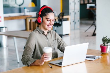 Mexico City 'deki ofiste ya da işyerinde bilgisayar ve kulaklıkla çalışan Latin bir kadın.
