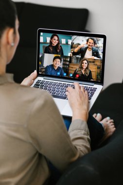 Latin Amerikalı bir kadının video konferans ekibindeki Meksikalı iş arkadaşlarıyla bilgisayar kullanarak Latin Amerika 'daki evinden yaptığı bir video görüşmesi için yaptığı görüntüler.