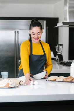 Latin Kadın mutfakta duruyor ve geleneksel Meksika ekmeği pişirmek için hamur yoğuruyor.