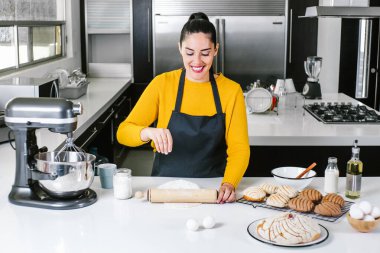 Latin Kadın mutfakta duruyor ve geleneksel Meksika ekmeği pişirmek için hamur yoğuruyor.