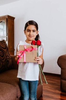 Latin küçük kız annesini tebrik ediyor ve ona çiçekler veriyor. Mutlu anneler günü için Mexico City 'de.