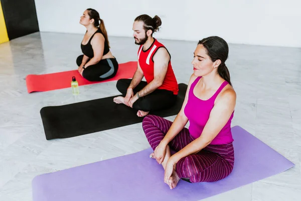 Group of young latin people meditating quiet in yoga studio in Latin America