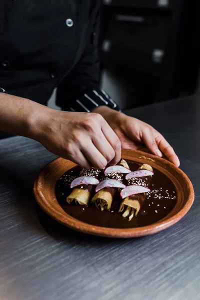 mexican woman cooking mole poblano enchiladas traditional food in a restaurant in Mexico