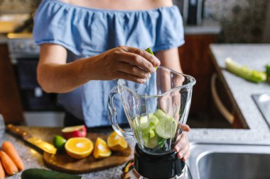 Latin Kadın Meksika 'da sağlıklı beslenme kavramında mutfakta yeşil smoothie veya detoks suyu yapıyor.