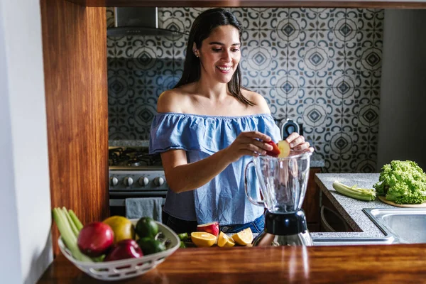 メキシコの健康的な食事のコンセプトで自宅でキッチンで緑のスムージーやデトックスジュースを作るラテン女性 — ストック写真