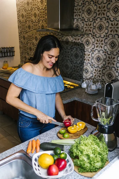 メキシコの健康的な食事のコンセプトで自宅でキッチンで緑のスムージーやデトックスジュースを作るラテン女性 — ストック写真