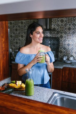 Latin Kadın Meksika 'da sağlıklı beslenme kavramında mutfakta yeşil smoothie veya detoks suyu yapıyor.