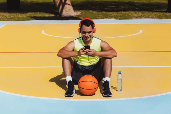 メキシコやラテンアメリカでヘッドフォンや携帯電話でバスケットボールをしている若いラテン人の肖像画 — ストック写真