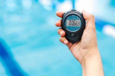 Meksika Latin Amerika 'daki yüzme havuzunda arka planda genç bir adamla birlikte bir kronometre tutuyor.