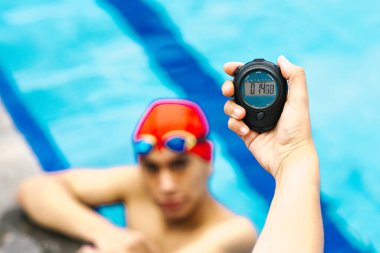 Meksika Latin Amerika 'daki yüzme havuzunda arka planda genç bir adamla birlikte bir kronometre tutuyor.