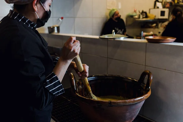 mexican woman cooking mole poblano food in a traditional clay pot in a restaurant in Mexico