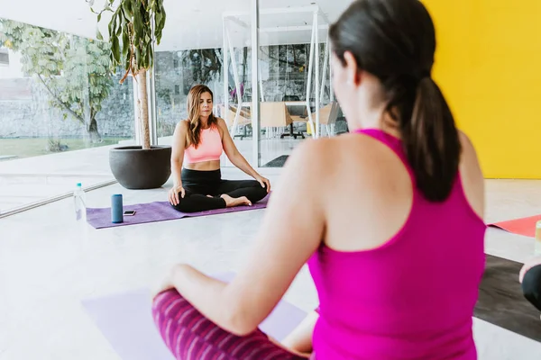 Two latin women doing yoga at the gym in Latin America