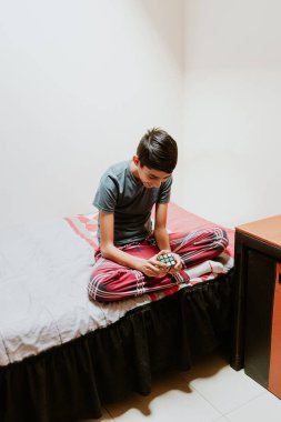 Latin Amerika 'da yatakta otururken bir Rubik küpünü çözen Latin çocuk.