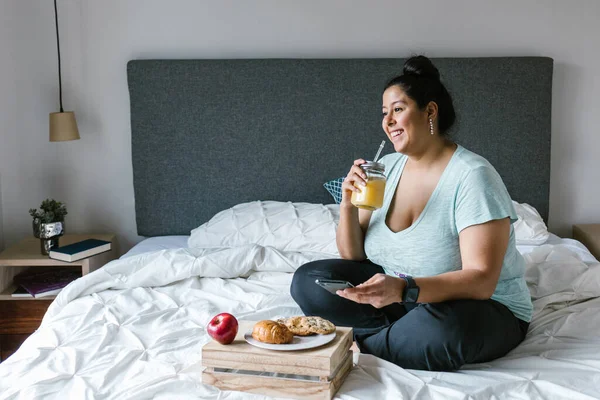 Kurviges Lateinamerikanisches Mädchen Mit Smartphone Beim Frühstück Und Orangensaft Bett — Stockfoto