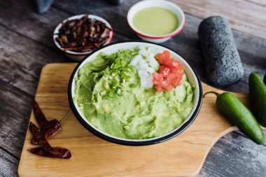Meksika 'daki ahşap bir masada taze malzemelerin yanında bir kase Guacamole.