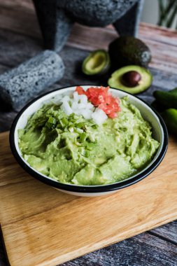 Meksika 'daki ahşap bir masada taze malzemelerin yanında bir kase Guacamole.
