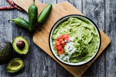 Meksika 'daki ahşap bir masada taze malzemelerin yanında bir kase Guacamole.