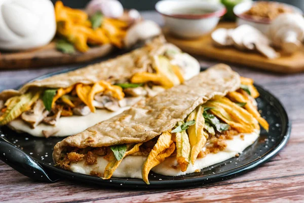 Traditional mexican quesadillas with squash blossom, melted oaxaca cheese, pork rind chicharron and mushrooms in Mexico City