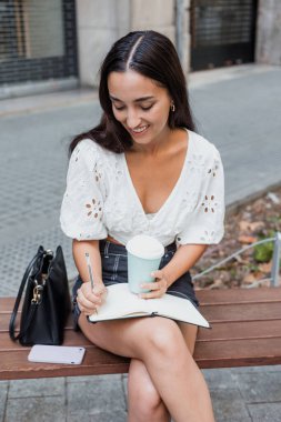 Latin Amerika 'nın şehir caddesindeki bir halk parkında not defterine yazan genç Latin kız öğrenci.