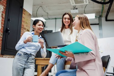 İş dünyasında takım çalışması yapan Latin kökenli genç kadınlar ve işkadını güçlendirme kavramında dizüstü bilgisayar ya da işyeri kullanan girişimciler