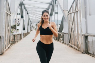 Şehirdeki şehir bölgesinde koşan genç İspanyol kadın, kadın koşucu.