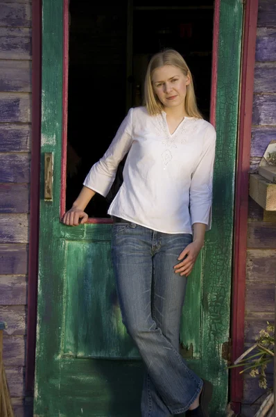 Pretty blonde woman standing in rustic doorway — Stock Photo, Image