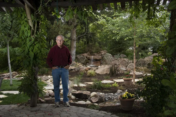 Пожилой человек, стоящий в саду — стоковое фото