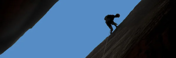 Silhouette of rock climber rappelling — Stock Photo, Image