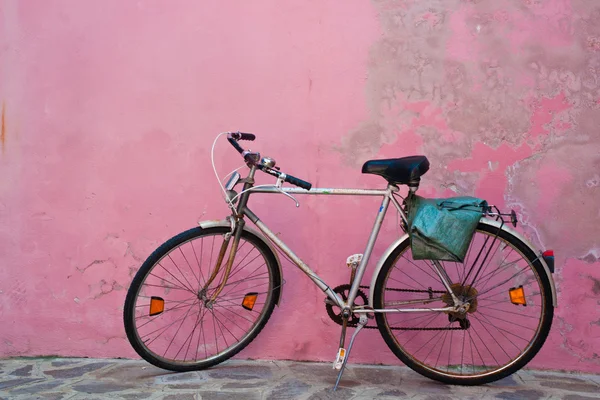 Bicicleta velha estacionada ao lado de uma parede rosa — Fotografia de Stock