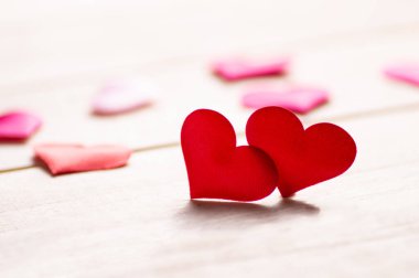 Odaklanamayan ışıklara karşı ahşap masada iki kırmızı kalbi kapat..