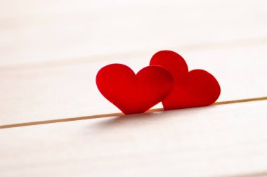 Odaklanamayan ışıklara karşı ahşap masada iki kırmızı kalbi kapat..