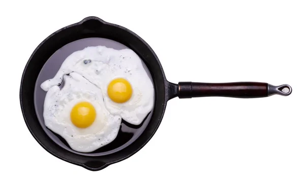 Gebakken twee eieren in zwarte pan geïsoleerd op witte achtergrond close-up — Stockfoto
