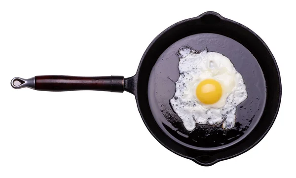Kızarmış bir yumurta siyah tavada, beyaz arka planda izole edilmiş. — Stok fotoğraf