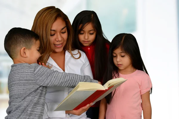 Mãe com três filhos lendo — Fotografia de Stock