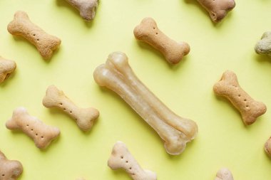 Sarı duvar kağıdı arka planında küçük renkli köpek kemiği deseni.