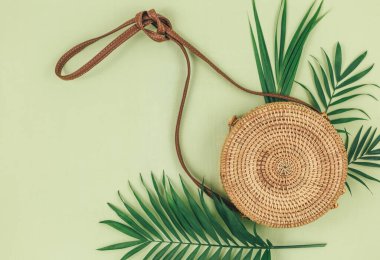 Tropik palmiye yaprakları, yeşil arka planda saman torbası. Moda tropikal desen. Moda kıyafetleri ve aksesuarlar. Düz yatıyordu. Yaz, tatil, tatil konsepti.