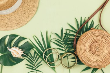 Tropik palmiye yaprakları, yeşil arka planda saman torbası. Moda tropikal desen. Moda kıyafetleri ve aksesuarlar. Düz yatıyordu. Yaz, tatil, tatil konsepti.