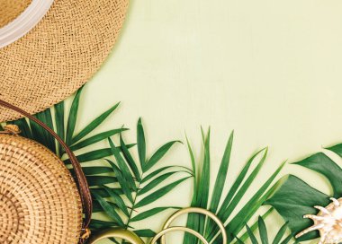 Tropik palmiye yaprakları, yeşil arka planda hasır şapka. Moda tropikal desen. Moda kıyafetleri ve aksesuarlar. Düz yatıyordu. Yaz, tatil, tatil konsepti.