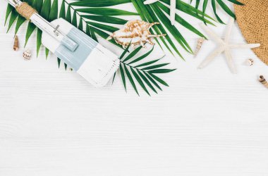 Tropik palmiye yaprakları, hasır şapka, denizyıldızı, beyaz ahşap arka planda deniz kabukları. Moda tropikal desen. Moda kıyafetleri ve aksesuarlar. Düz yat, kapat. Yaz, tatil, tatil konsepti.