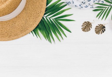 Tropik palmiye yaprakları, hasır şapka, denizyıldızı, beyaz ahşap arka planda deniz kabukları. Moda tropikal desen. Moda kıyafetleri ve aksesuarlar. Düz yat, kapat. Yaz, tatil, tatil konsepti.