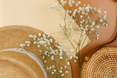 Tropik hasır şapka, çanta, bej kahverengi arka planda yaz çiçekleri. Moda tropikal desen. Moda kıyafetleri ve aksesuarlar. Düz yat, kapat. Yaz, tatil, tatil konsepti.