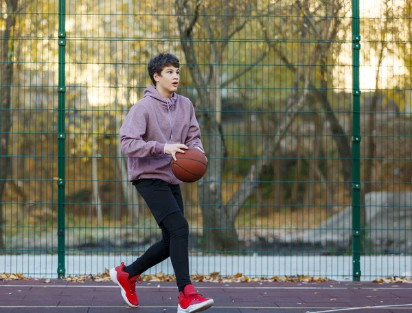 Симпатичный Подросток Оранжевым Баскетбольным Мячом Играет Баскетбол Уличной Площадке Весной — стоковое фото
